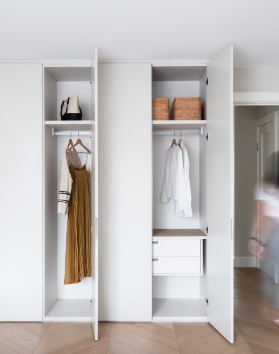 Floor to ceiling closet system with two doors open showing interior closet with motion blur of person walking out of the room