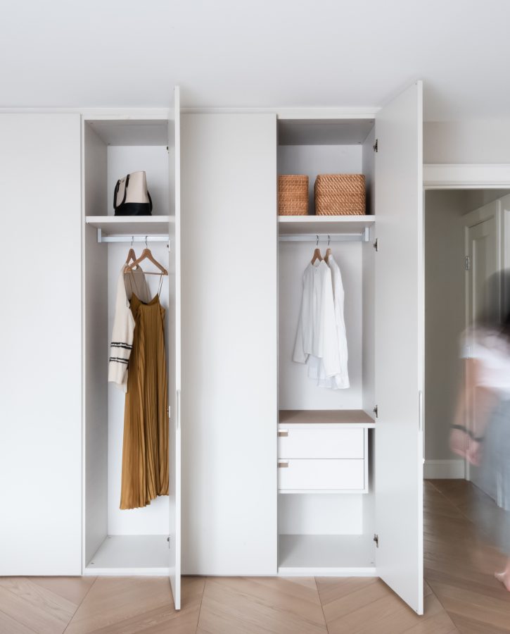 Floor to ceiling closet system with two doors open showing interior closet with motion blur of person walking out of the room