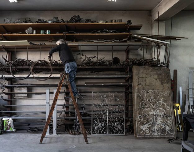 Artisan standing on ladder tinkering in iron workshop
