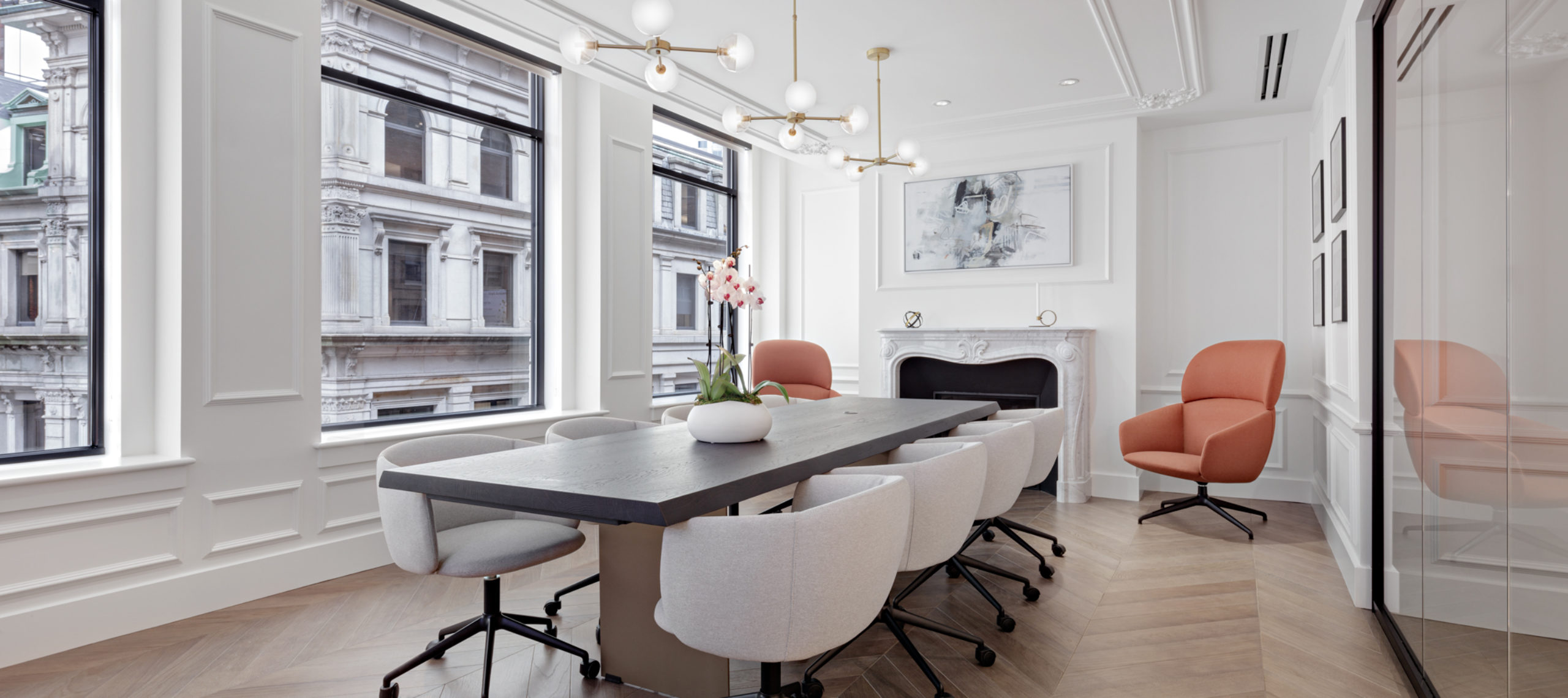 Angled view of Boston office conference room with beige chairs, dark wood table, marble fireplace and designer lighting.
