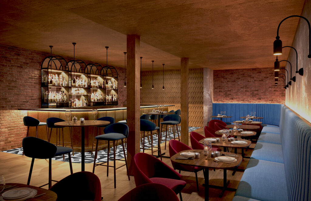 Angled view of Sabina Mezcaleria with long velour banquette, custom furniture and bar area